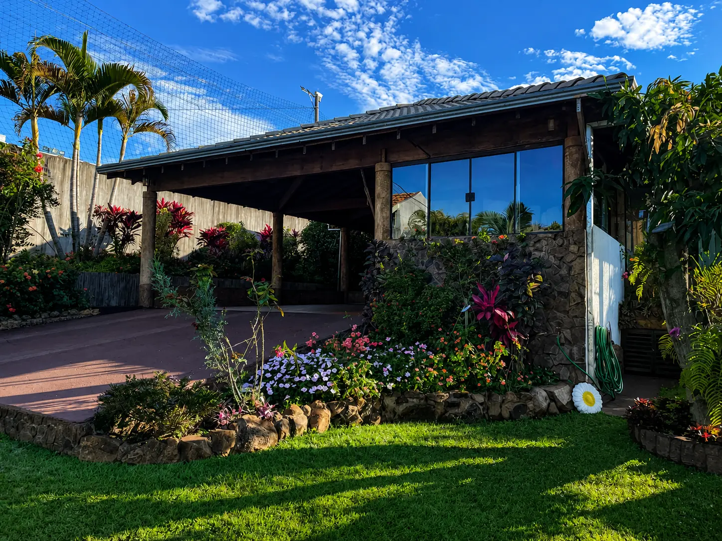 Fachada em pedra com garagem coberta e jardim florido