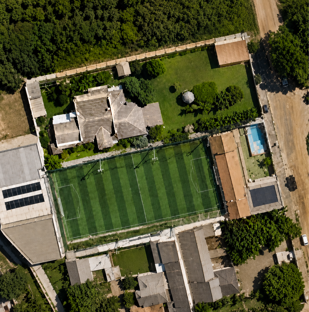 Vista aérea da propriedade com campo de futebol society, piscina e edículos